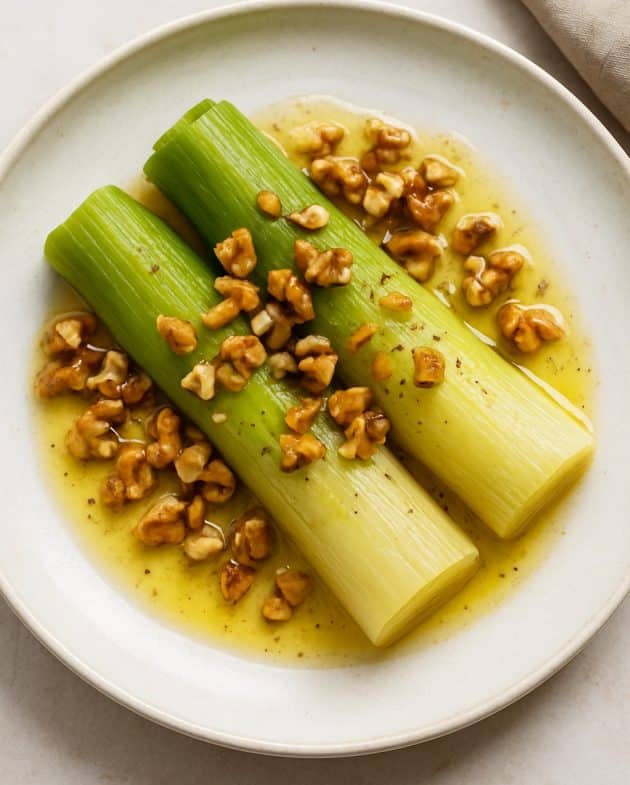 Französischer Lauchsalat mit Senf-Dressing und Walnüssen auf einem weißen Teller